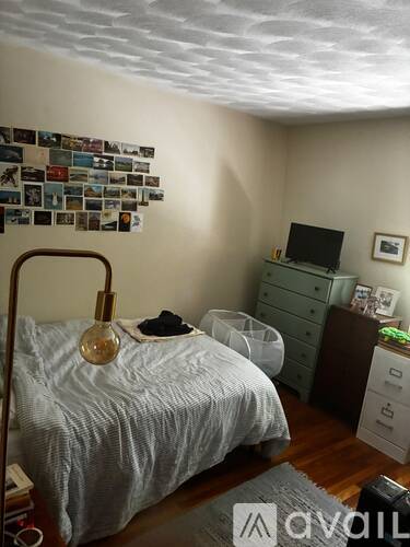 A bedroom with a bed, dresser, and a wall of pictures.