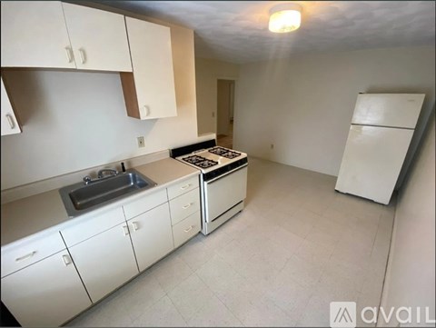A kitchen with white cabinets and appliances is available for rent.