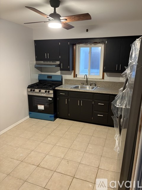 A kitchen with black cabinets and a blue stove top oven.
