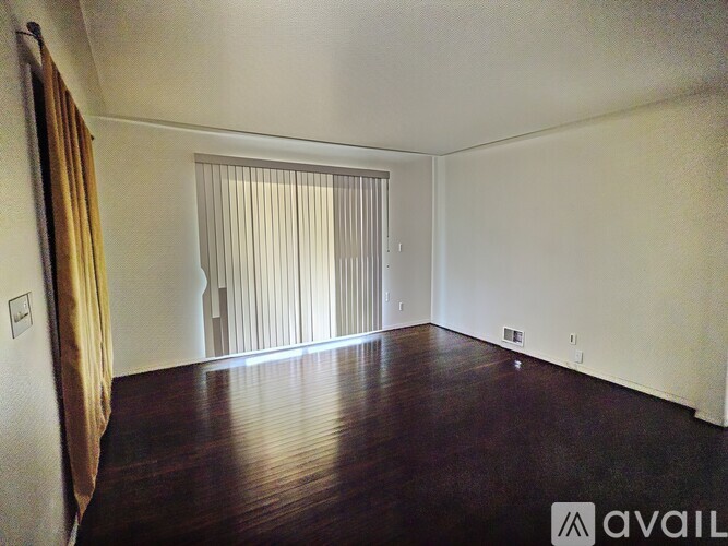 A room with wooden floors and a window with blinds.