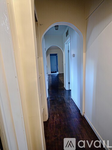 A hallway with a wooden floor and white walls.