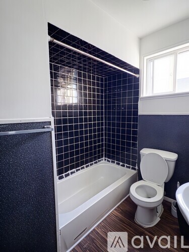 A bathroom with a toilet, a bathtub and a window.