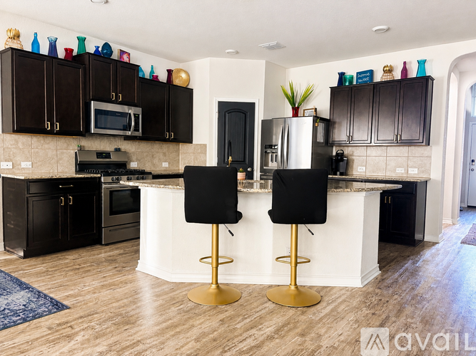 A kitchen with black cabinets and a white island.