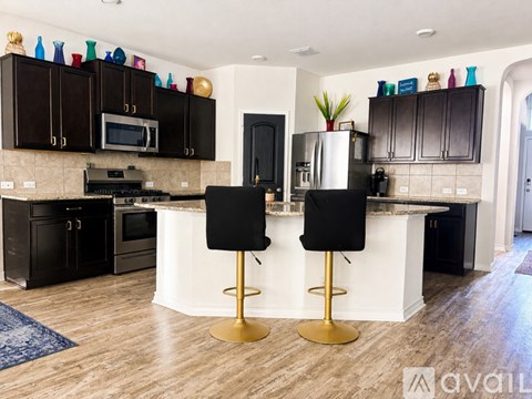 A kitchen with black cabinets and a white island.