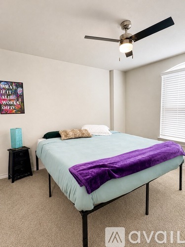 A bedroom with a bed covered in a purple blanket.