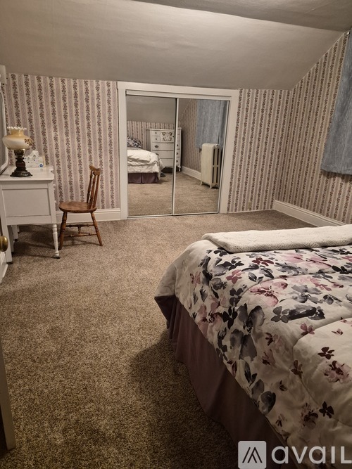 A bedroom with a bed, chair, and a dresser with a lamp on it.