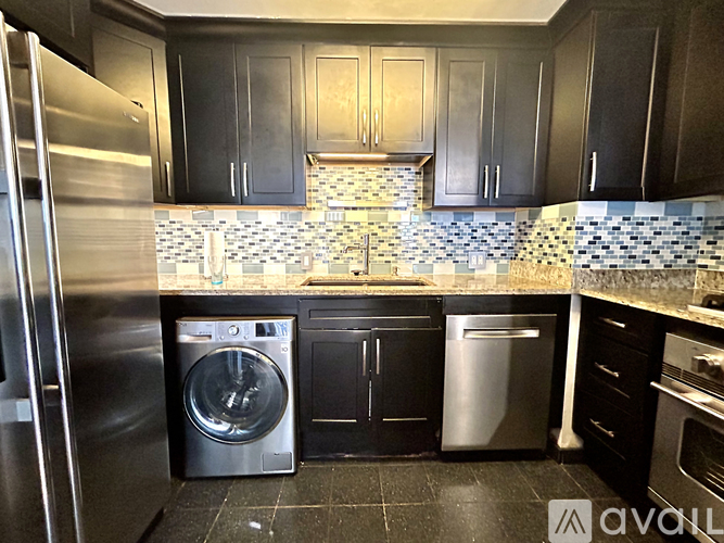 A kitchen with black cabinets and a stainless steel refrigerator.