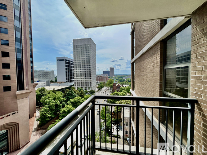 A balcony overlooks a cityscape with tall buildings and greenery.