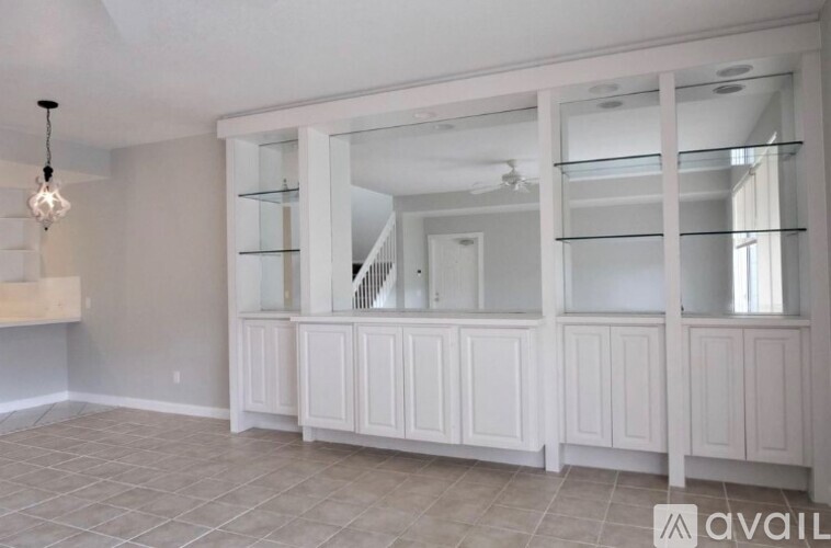 A room with a white cabinet and glass shelves.
