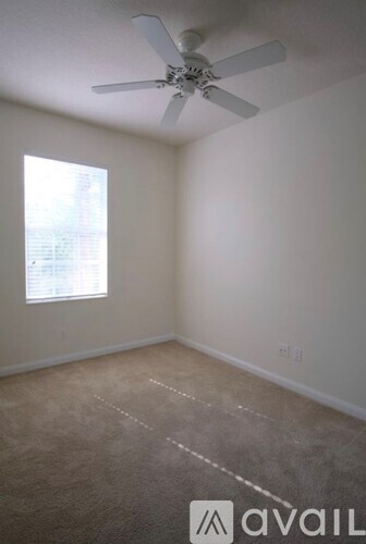 A room with a ceiling fan and a window letting in light.