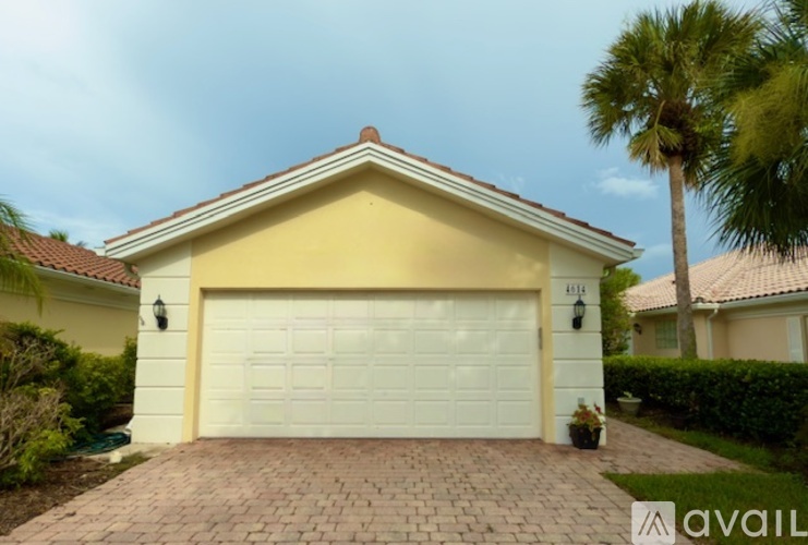 A house with a white garage door and a brick driveway.