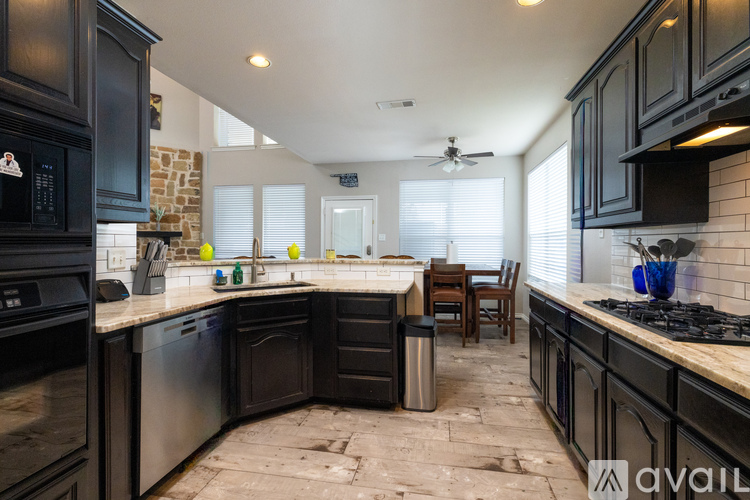 A kitchen with black cabinets and a stone wall.