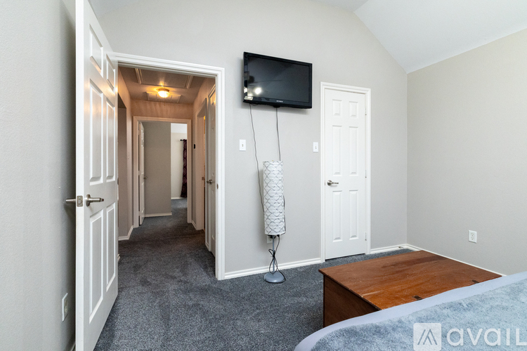 A bedroom with a bed, desk, and television.
