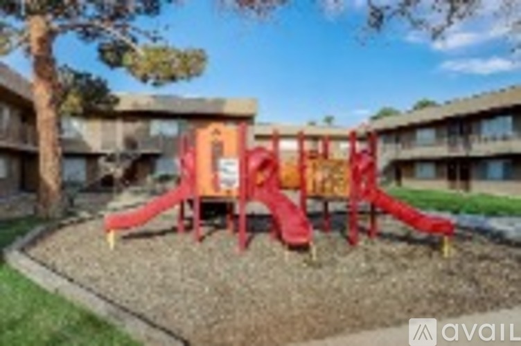 A playground with a red slide in front of a building.