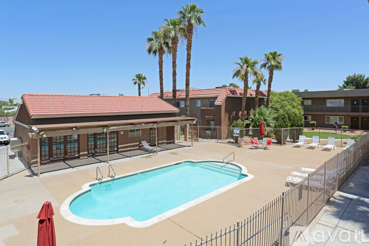 A pool surrounded by a fence and palm trees.