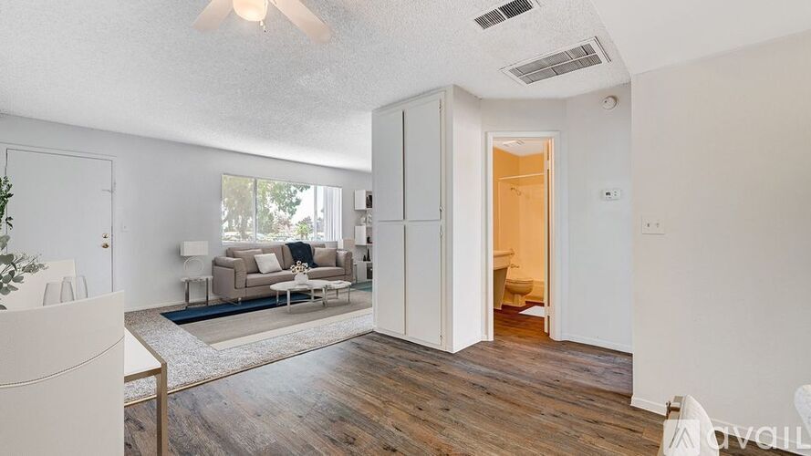A living room with a couch, a rug, and a ceiling fan.