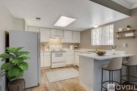 A kitchen with white appliances and a white island with bar stools.