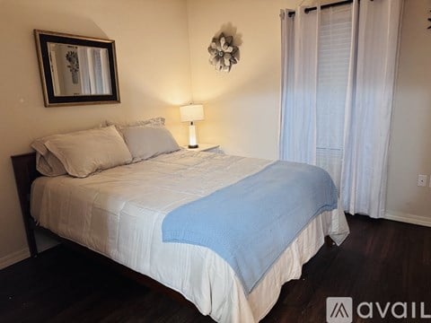 A bedroom with a bed, a mirror, a lamp, and a flower decoration on the wall.