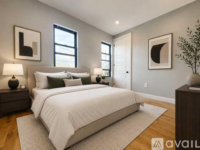 A bedroom with a large bed, two lamps, and framed artwork on the wall.