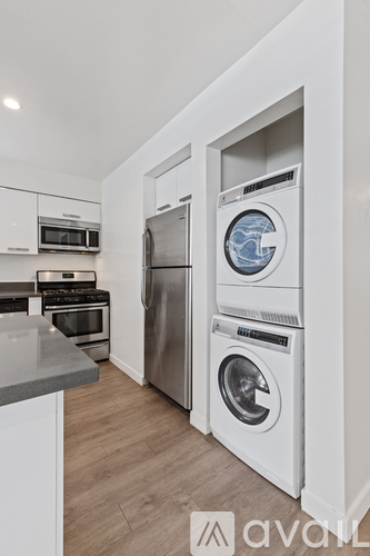 A modern kitchen with stainless steel appliances and a washer and dryer in the laundry area.