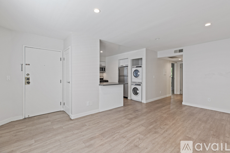 A spacious, empty room with a washer and dryer stacked together.