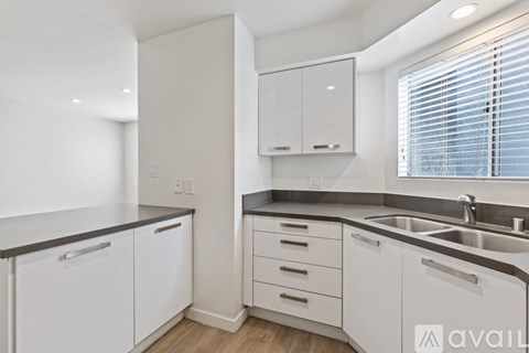A kitchen with white cabinets and a black countertop.