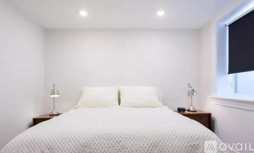 A bedroom with a bed, two lamps, and a window.
