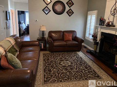 A living room with a brown leather couch and a fireplace.