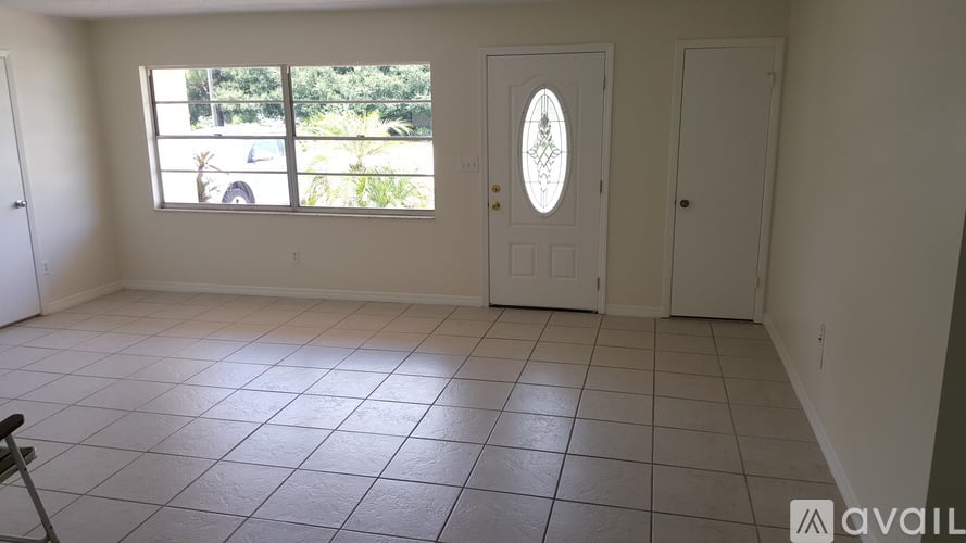 A room with a white door and a window with a view of a parking lot.
