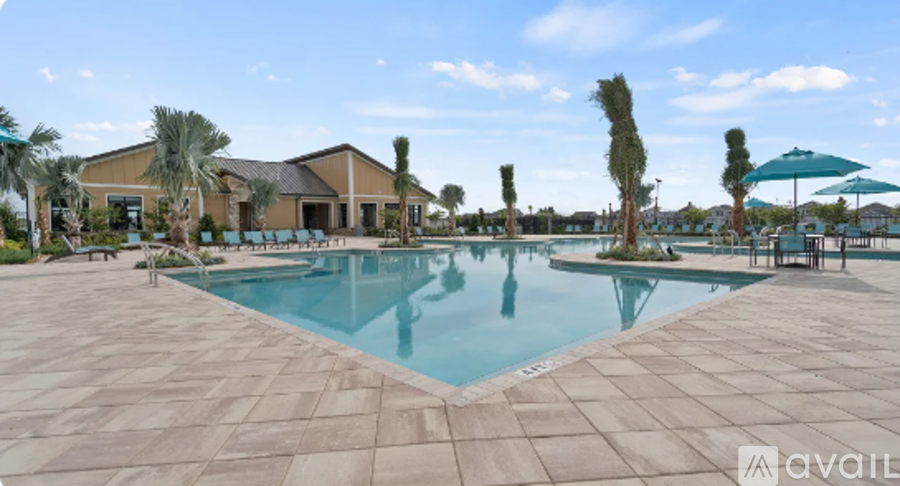 A large swimming pool with a tiled floor and a house in the background.