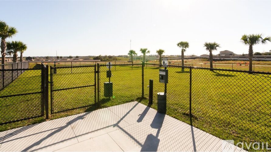 A fenced area with a walkway and green trash bins.
