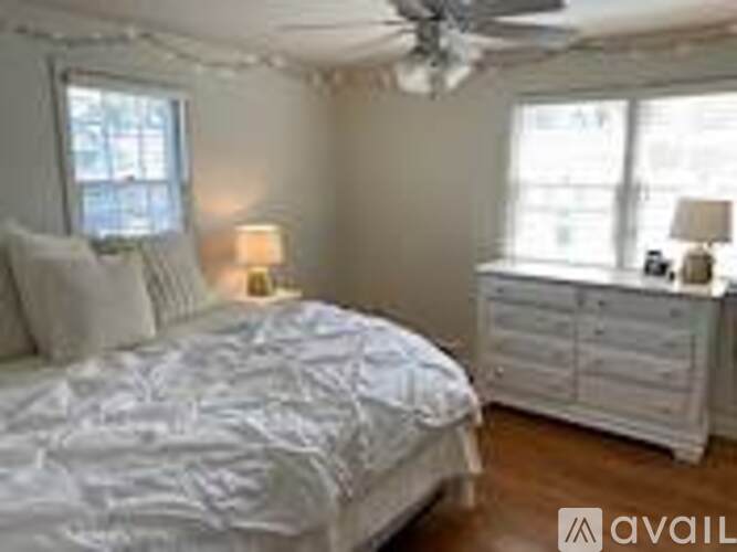 A bedroom with a bed, dresser, and window.