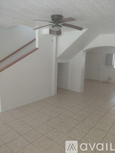A room with a ceiling fan and tiled flooring.
