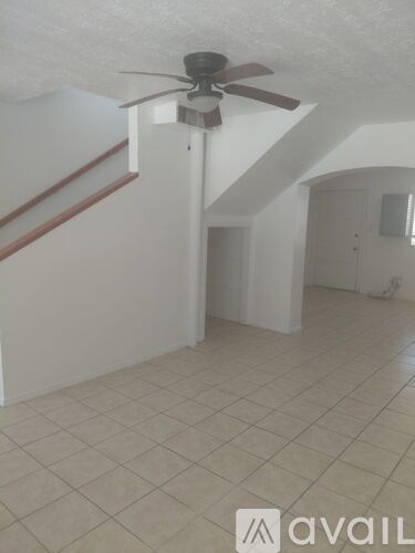 A room with a ceiling fan and tiled flooring.