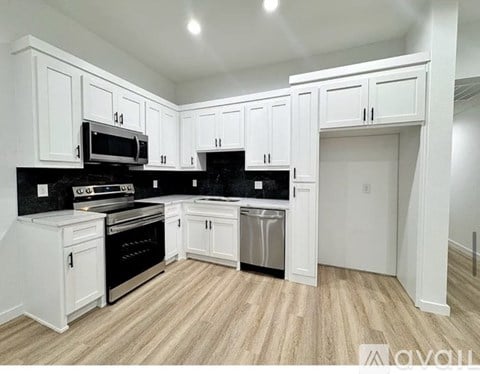 A kitchen with white cabinets and black countertops.