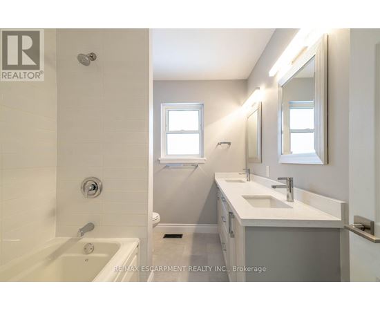 A white bathroom with a tub, sink, and mirror.