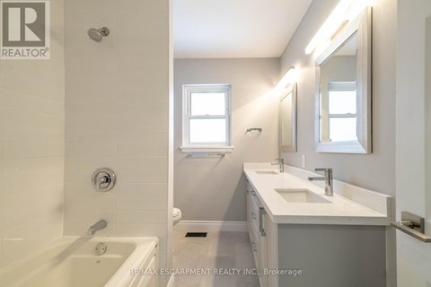 A white bathroom with a tub, sink, and mirror.