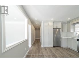 A well-lit kitchen with white cabinets and a stainless steel refrigerator.
