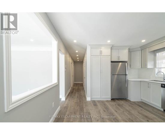 A well-lit kitchen with white cabinets and a stainless steel refrigerator.