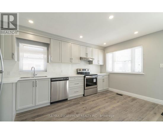 A kitchen with white cabinets and a stainless steel dishwasher and oven.