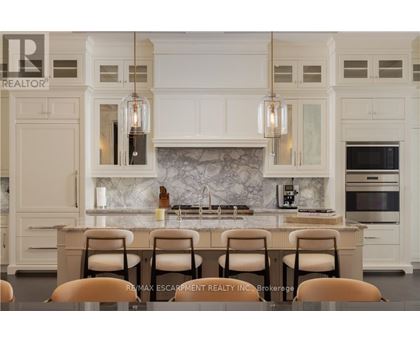 A kitchen with white cabinets and a marble backsplash.