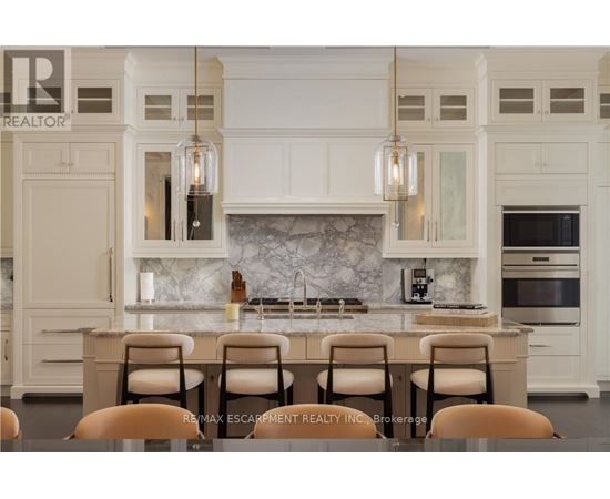 A kitchen with white cabinets and a marble backsplash.
