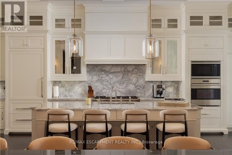 A kitchen with white cabinets and a marble backsplash.