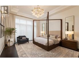 A bedroom with a four poster bed, a grey armchair, a side table with a lamp and a potted plant.