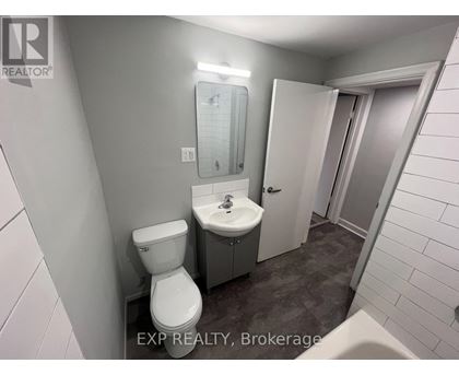 A bathroom with a toilet, sink, and mirror.