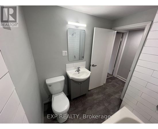 A bathroom with a toilet, sink, and mirror.