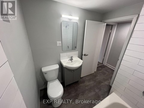 A bathroom with a toilet, sink, and mirror.