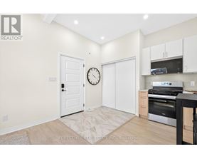 A kitchen area with a clock on the wall and a door to the right.