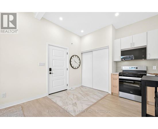 A kitchen area with a clock on the wall and a door to the right.