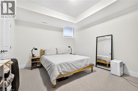 A bedroom with a bed, nightstand, and a mirror.